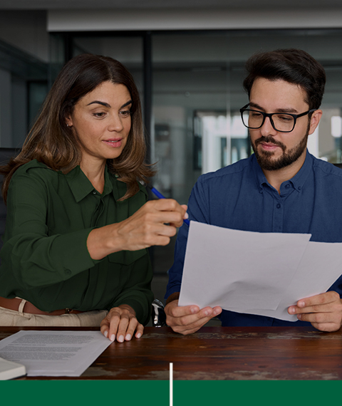 Deux personnes consultent ensemble des documents en lien avec un projet de fabrication de composantes de bois franc sur mesure.