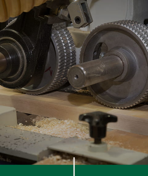 Machine industrielle de fabrication de composantes de bois franc sur mesure et planches de bois en cours de transformation.